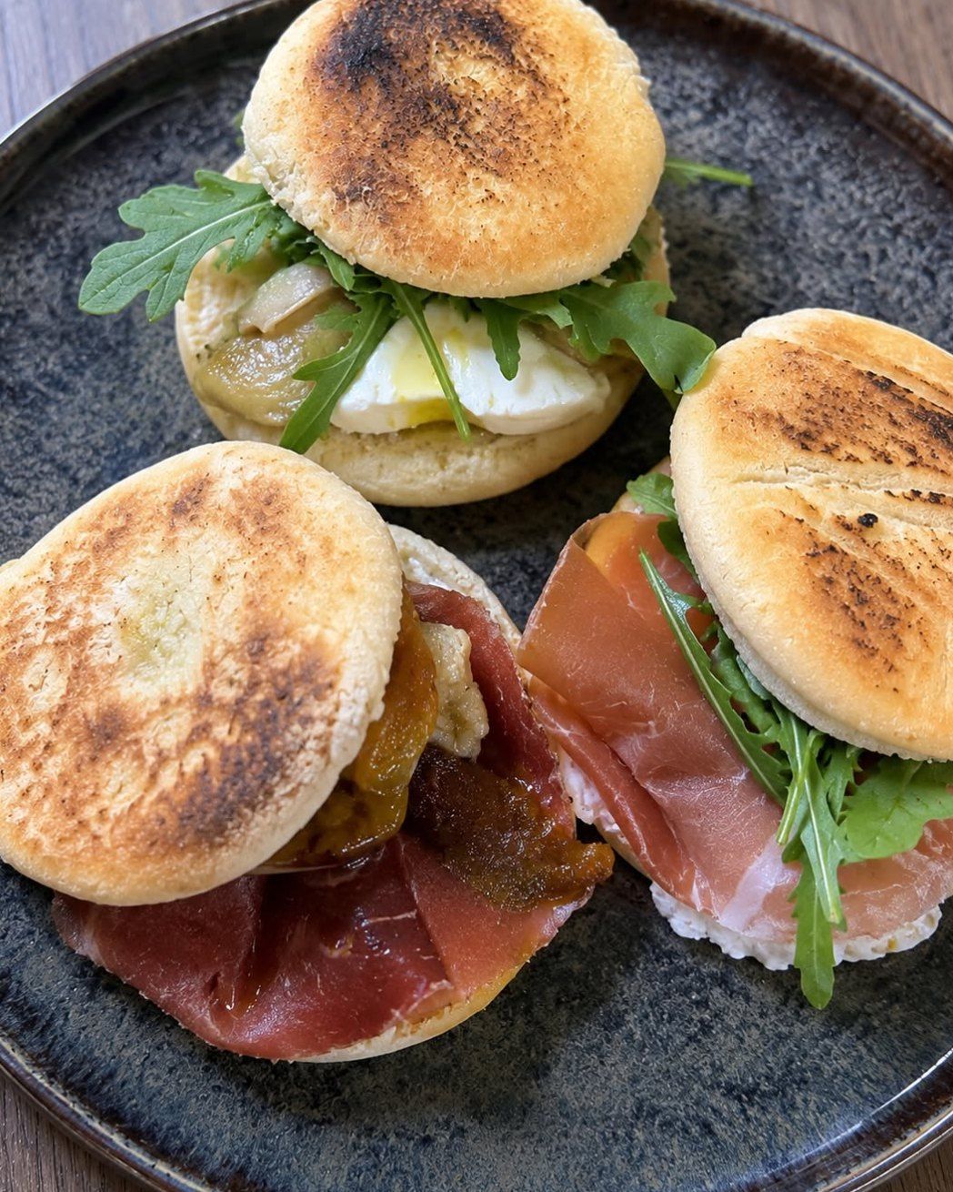 Trois tigelles garnies sur une assiette en grès : jambon de Parme, roquette, stracciatella